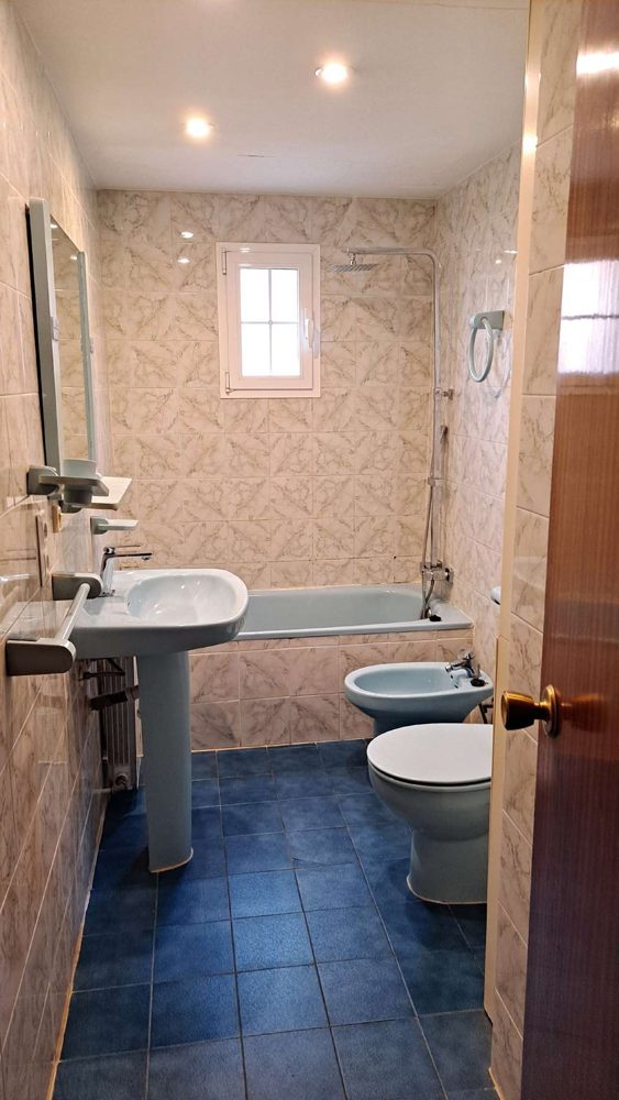 Baño antes de la reforma, con bañera azul y suelo de gresite azul