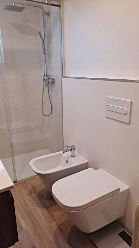 Ducha con mampara de cristal y sanitarios suspendidos