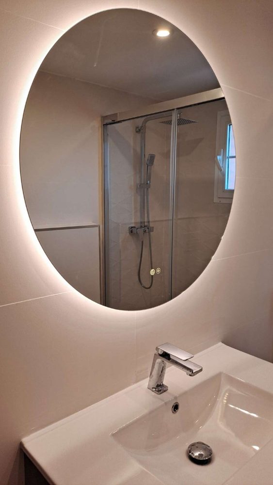 Lavabo con mueble suspendido y espejo redondo con luz LED