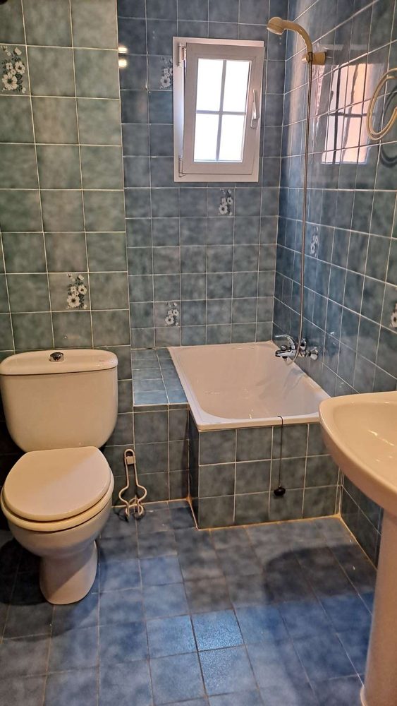 Baño antes de la reforma, con alicatado verde y bañera