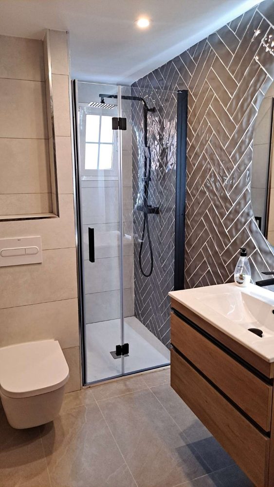 Baño reformado por Vita Reformas con ducha de perfilería negra y azulejo en espiga