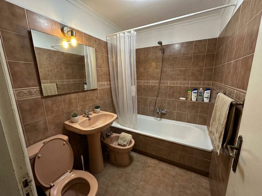 Baño antiguo con alicatado marrón y bañera antes de la reforma