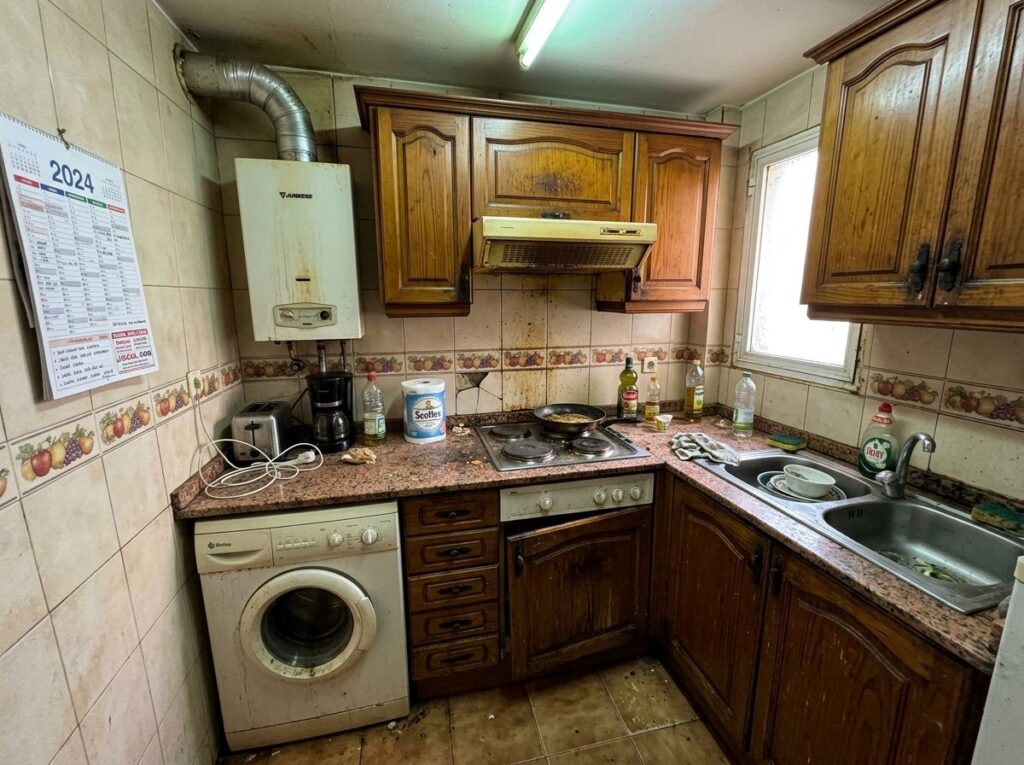Cocina antigua con calentador y muebles de madera antes de la reforma